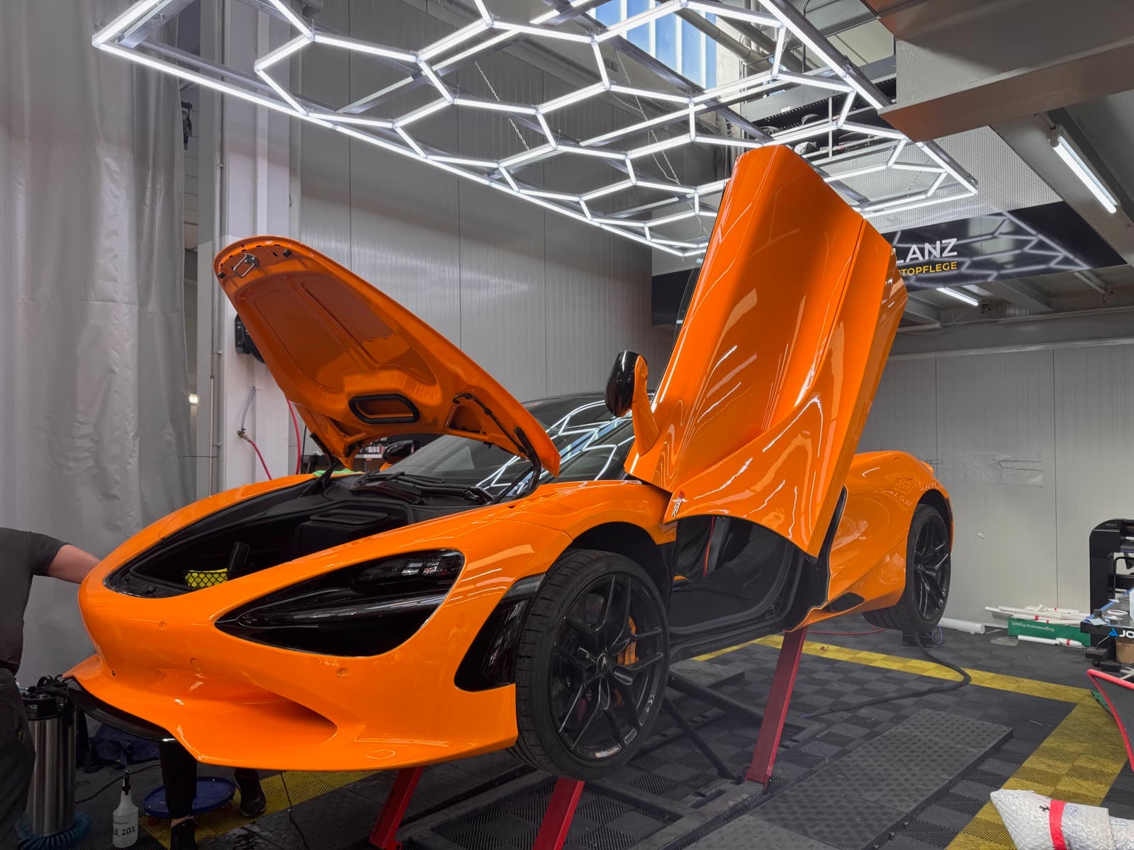 Oranger McLaren 720S mit geöffneten Türen während der PPF-Folierung